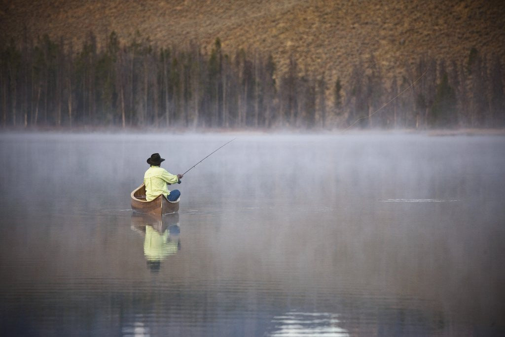Detail of Man fishing on foggy lake by Corbis