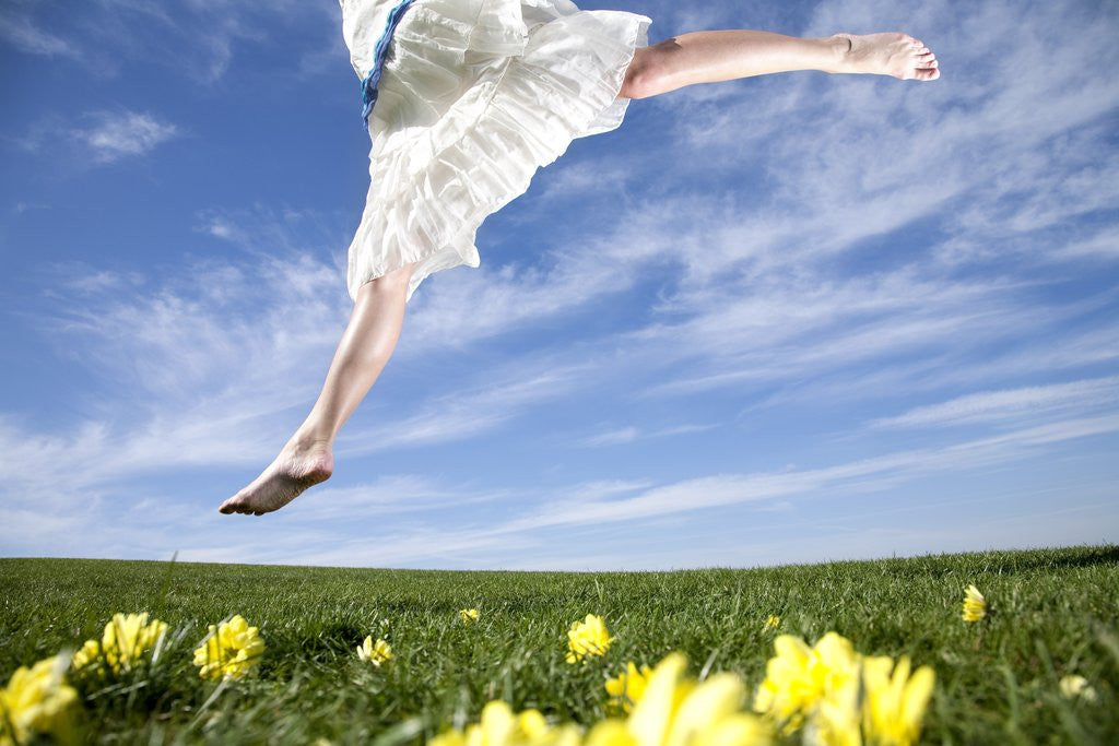 Detail of Young woman in park jumping on lawn by Corbis