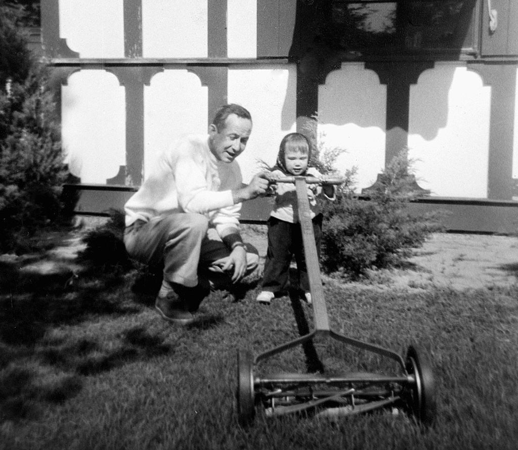 Detail of A father show his two year old daughter how to mow the lawn, ca. 1956 by Anonymous