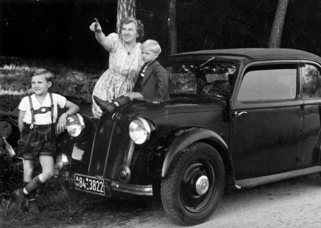 Detail of Mother stands next to her two sons sitting on the hood of their Mercedes automobile, ca. 1948 by Anonymous