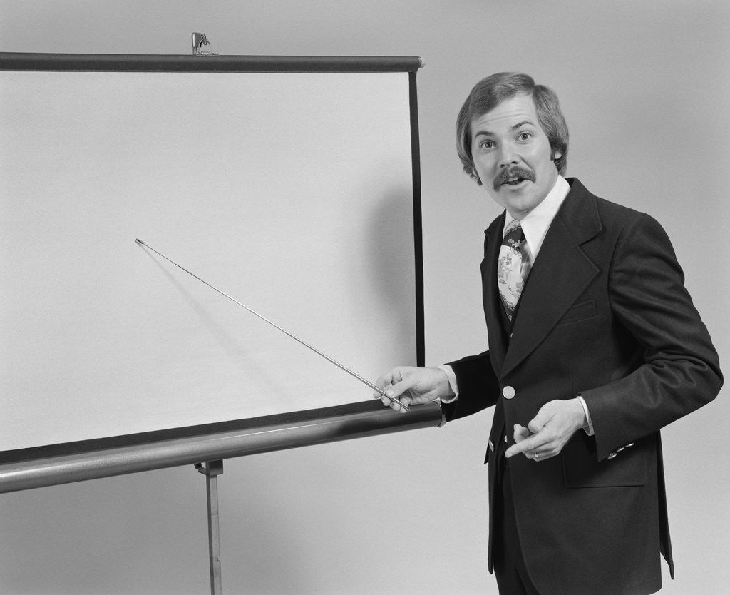 Detail of Young man speaking pointing to blank slide screen for presentation by Anonymous