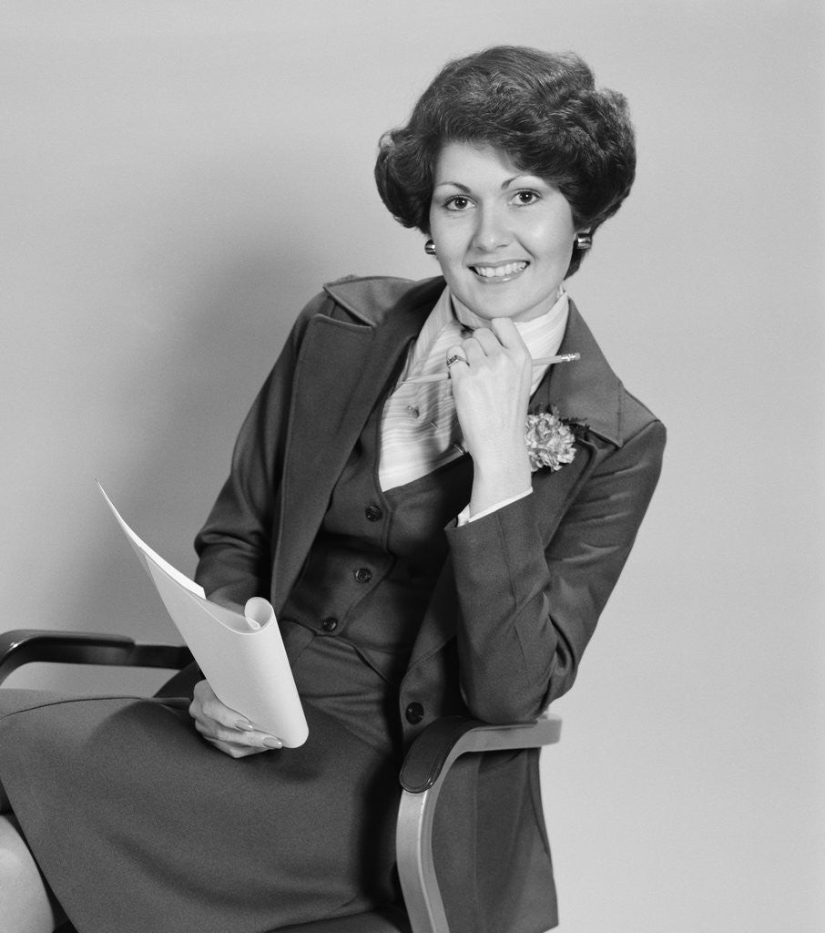 Detail of Smiling woman sitting in office chair holding papers by Anonymous
