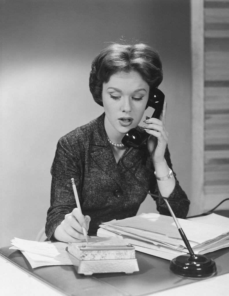 Detail of Brunette business woman sitting desk talking telephone writing note on calendar by Anonymous