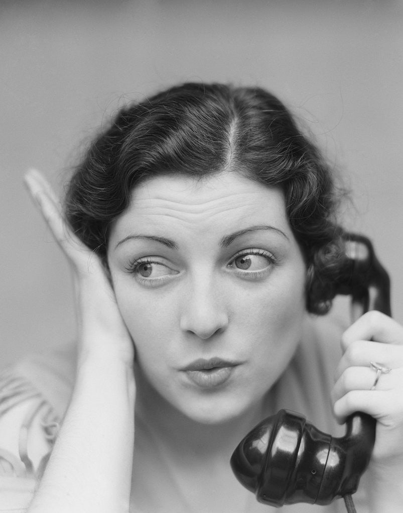 Detail of Young brunette woman with surprised expression hand to head talking on telephone by Anonymous