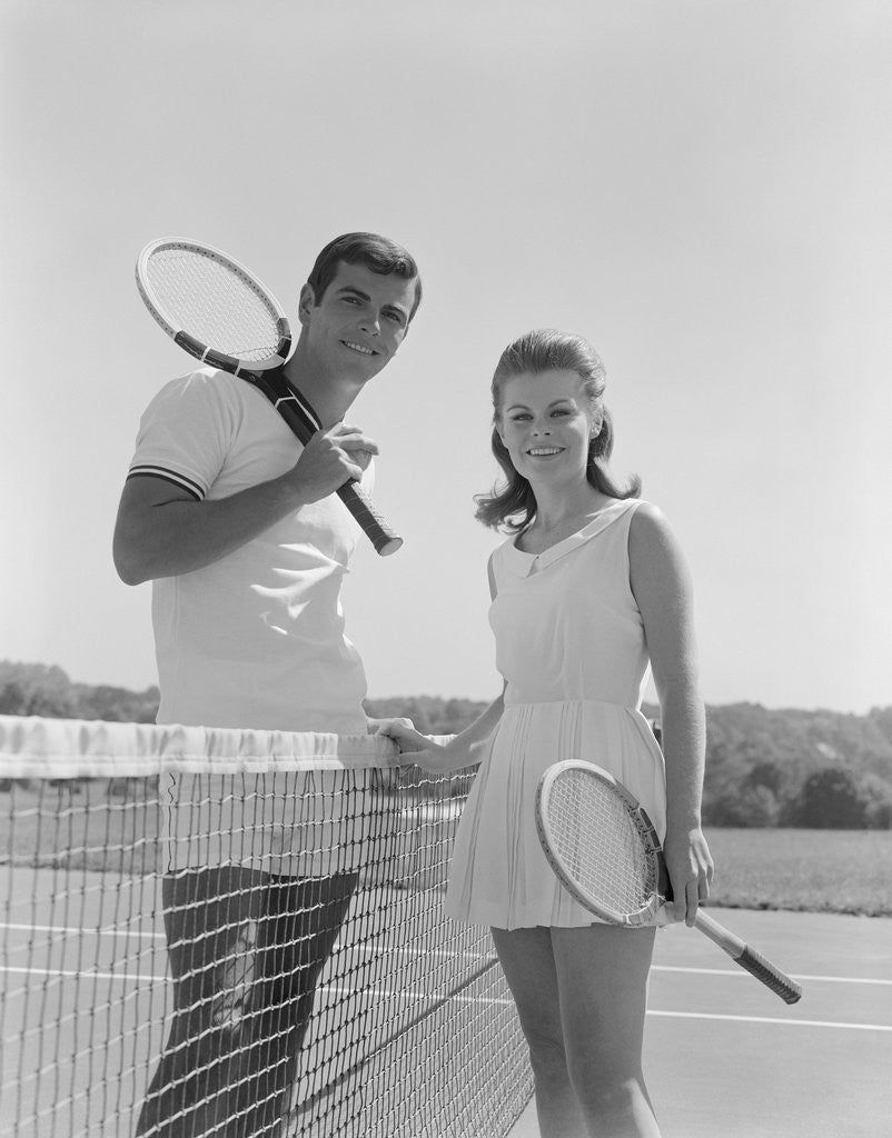 Detail of Portrait tennis couple man woman holding racquets standing by net by Anonymous