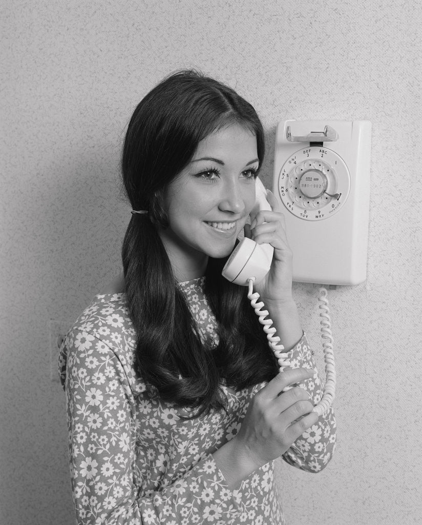 Detail of Smiling teenage girl talking on rotary wall telephone by Anonymous
