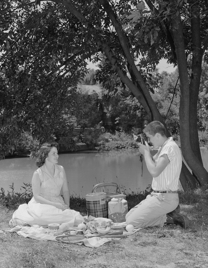 Detail of Teenage couple picnic boy taking photograph of girl outdoors by Corbis