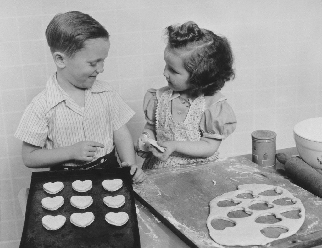 Detail of Young smiling girl and boy baking heart shaped valentine cookies by Corbis