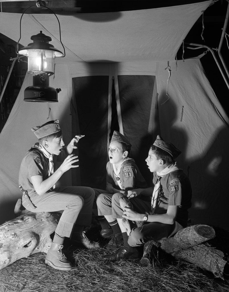 Detail of 3 boy scouts sitting tent night telling ghost stories by Corbis