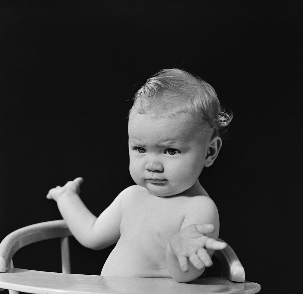Detail of Baby in high chair making shrugging gesture by Anonymous