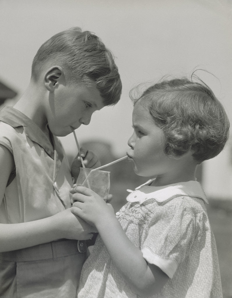 Detail of Children boy girl sharing drinking glass using straws by Anonymous