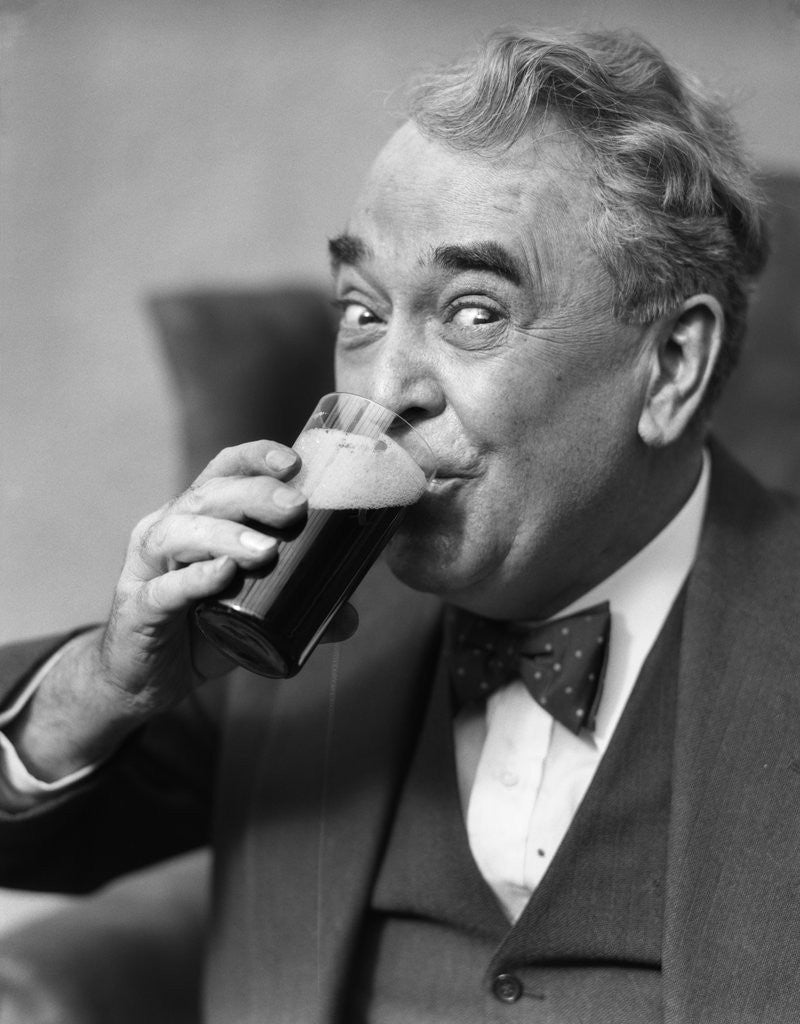 Detail of Smiling eyes of senior man drinking beer from glass by Corbis