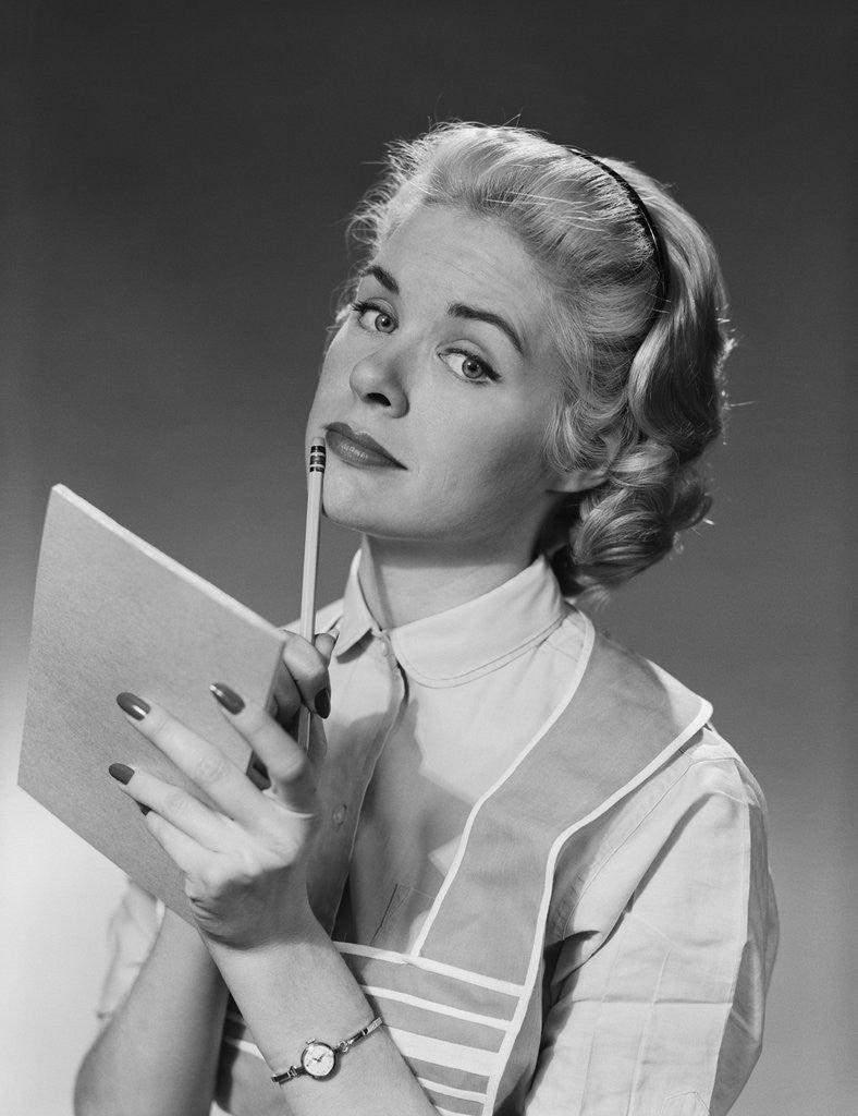 Detail of Blond woman wearing apron writing pad in hand pencil to chin thinking by Corbis