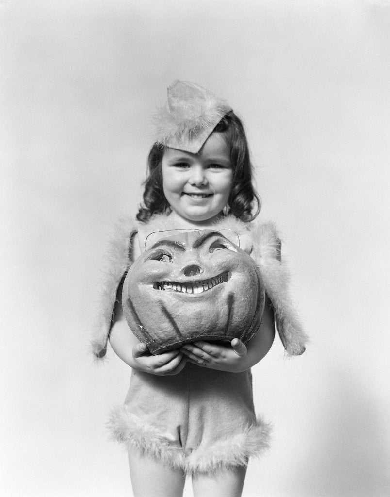 Detail of Happy smiling little girl in costume holding a papier-mache pumpkin head by Anonymous