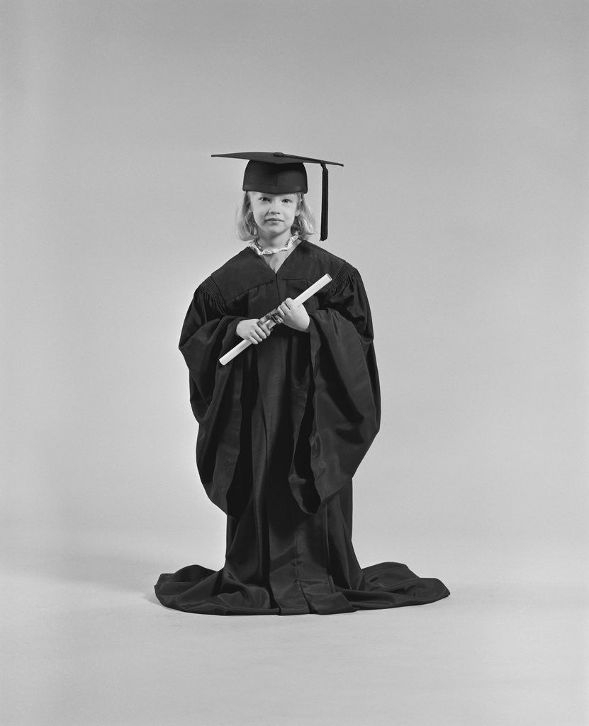 Detail of Girl wearing graduation cap gown holding diploma by Corbis