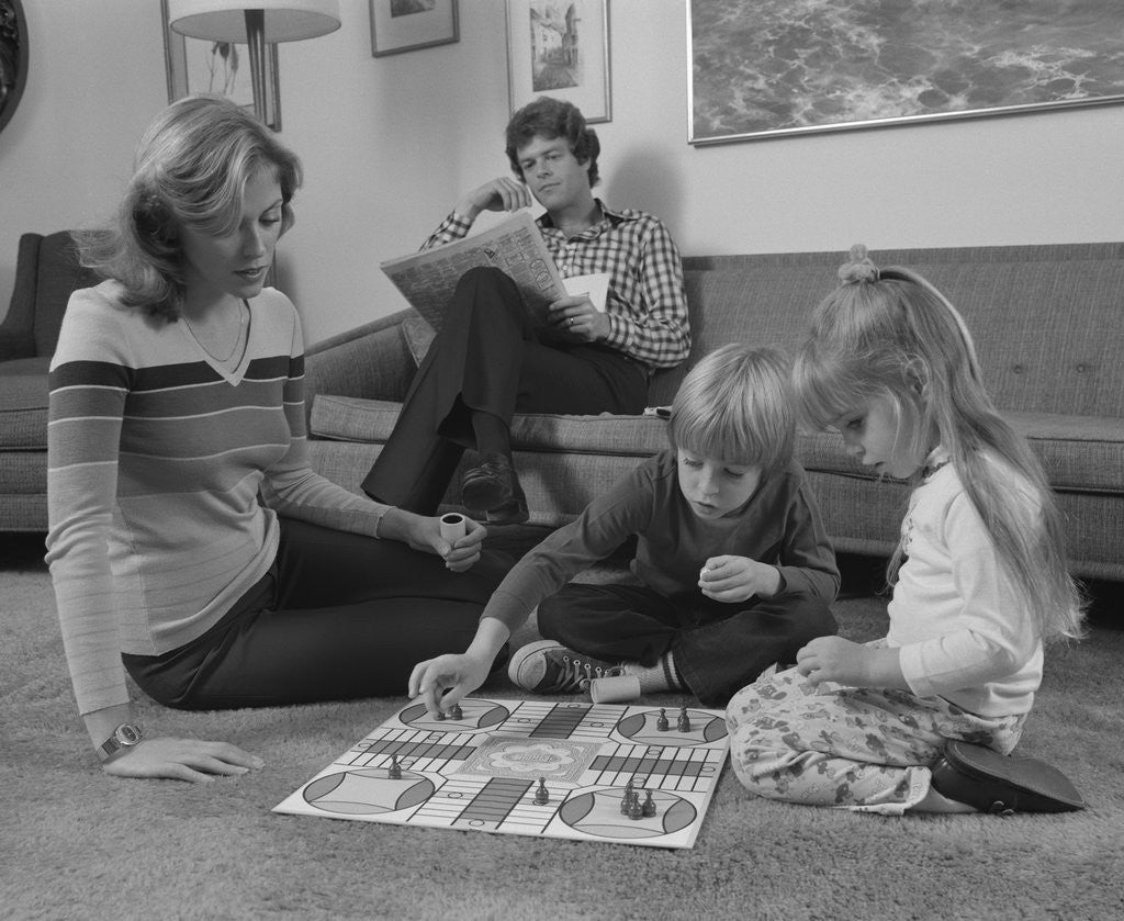 Detail of Family mother kids playing board game living room floor father reading newspaper by Anonymous