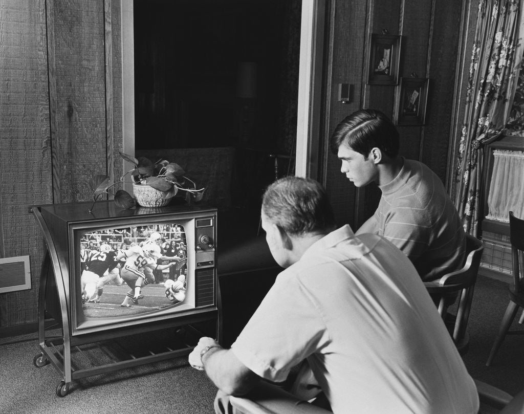 Detail of Teen boy watching football game on television with adult dad by Anonymous