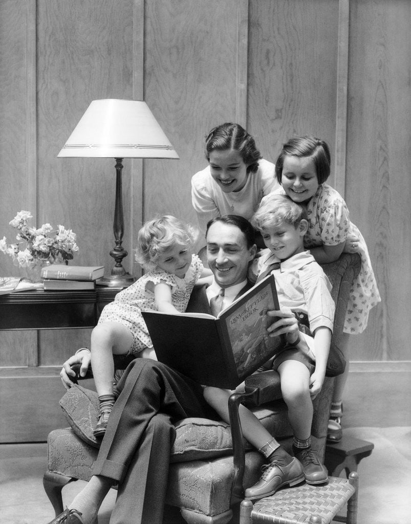 Detail of Father reading to family in chair by Corbis