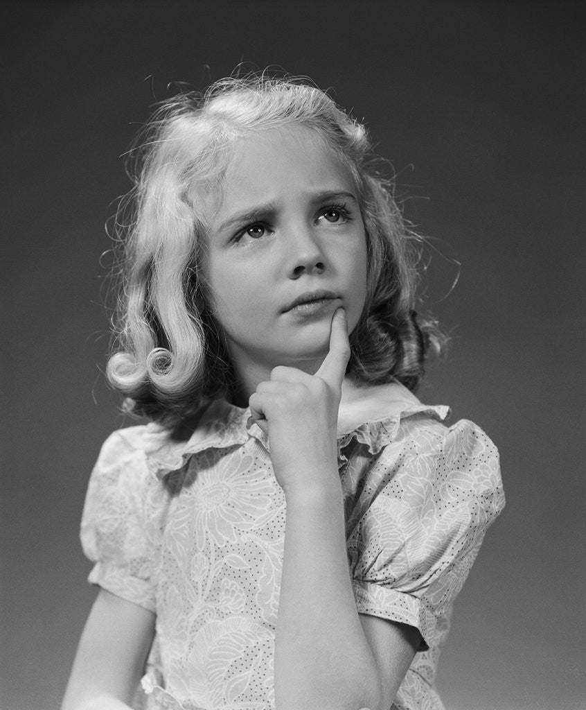 Detail of Blond girl portrait finger to chin thinking serious expression by Corbis