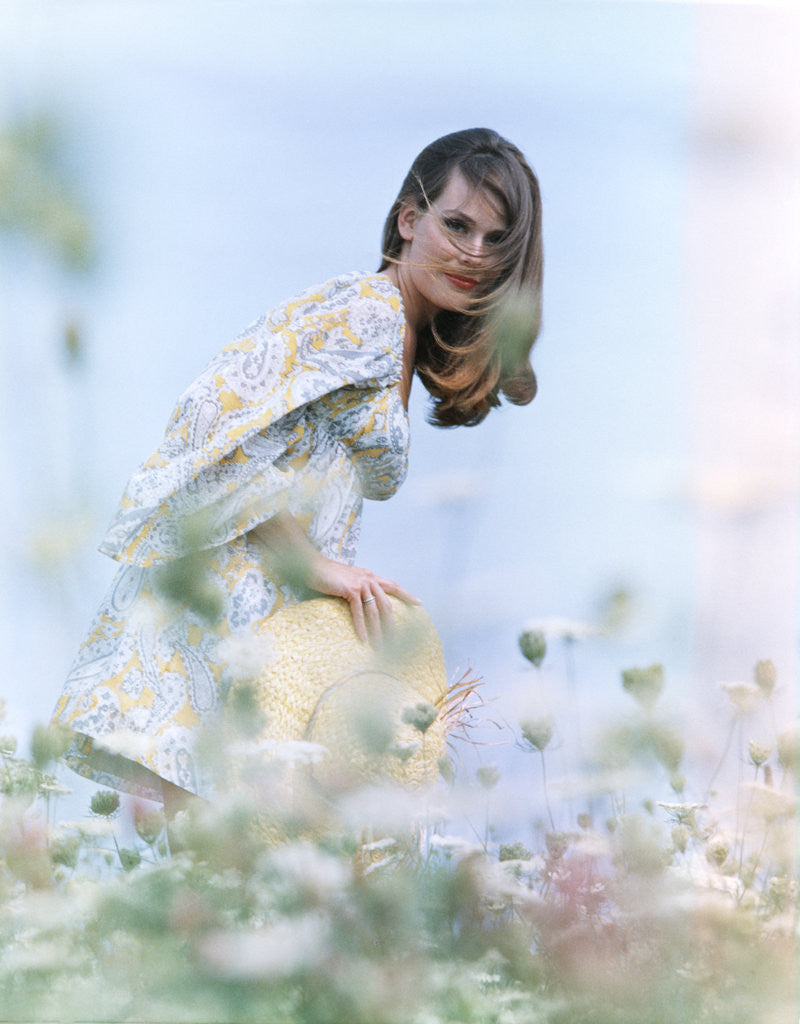 Detail of Young woman field of flowers print dress straw hat by Anonymous