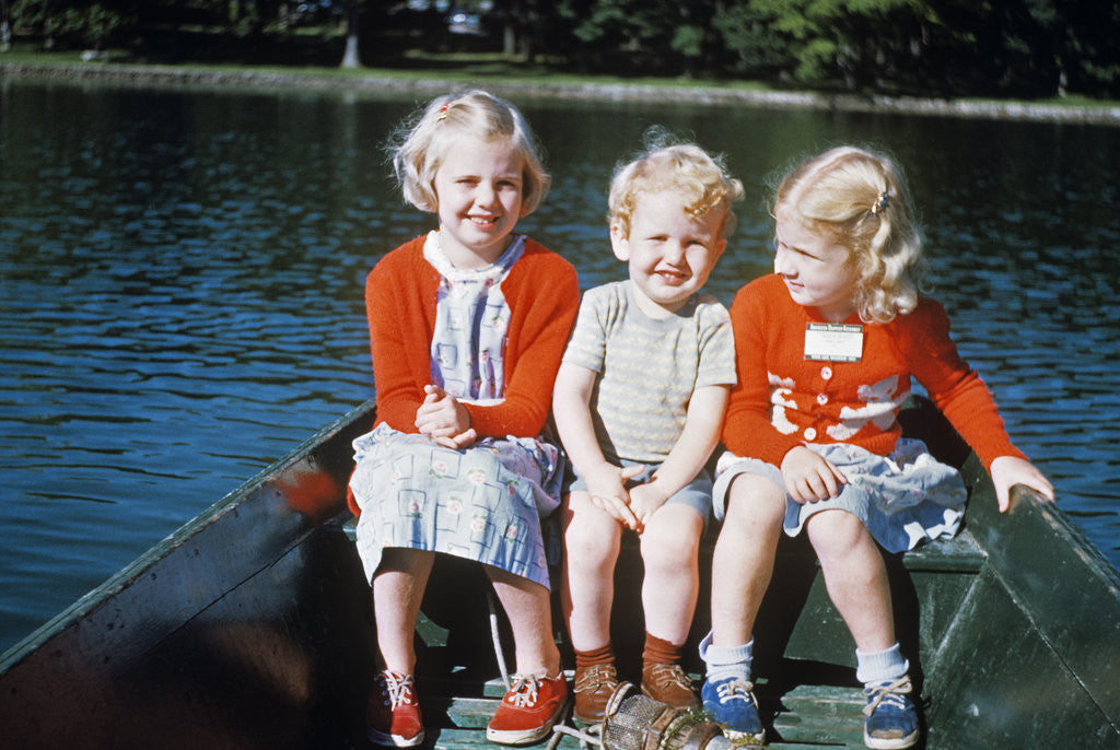 Detail of Boy and two girls in red sweaters sitting in back of rowboat by Anonymous