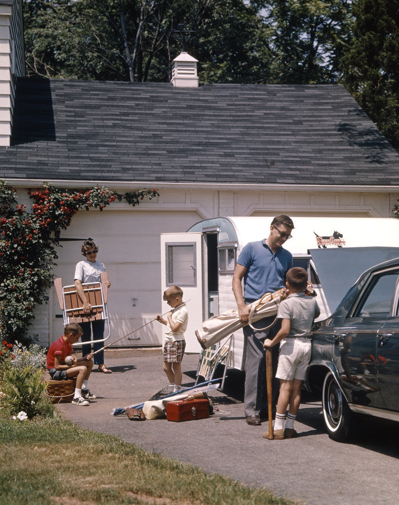 Detail of Family father mother 3 sons loading car and trailer for camping vacation by Anonymous