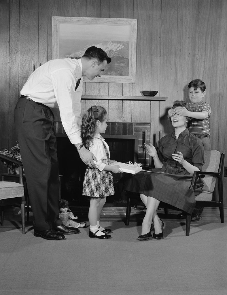 Detail of Family living room woman mother getting surprise gift from children daughter son husband by Anonymous