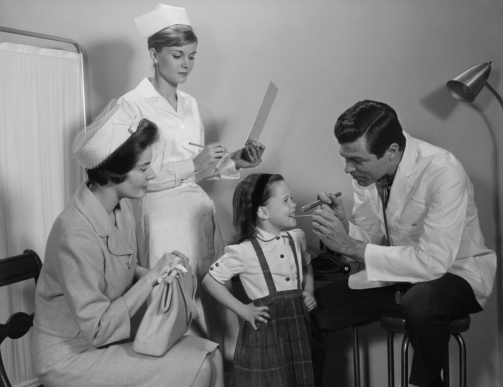 Detail of Mother sitting watching man pediatric doctor woman nurse checking on smiling little girl patient by Anonymous