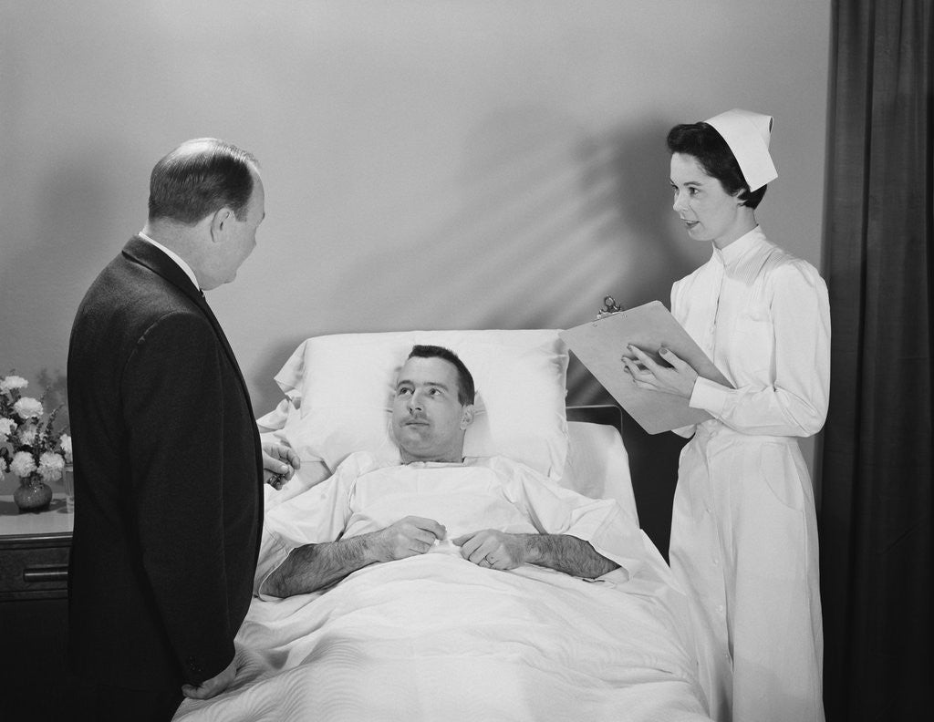 Detail of Man doctor woman nurse talking with male patient lying in hospital bed by Anonymous