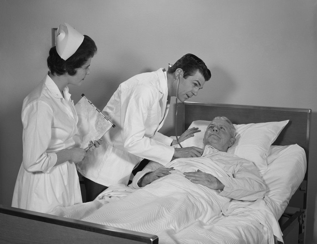 Detail of Doctor and nurse checking on elderly male patient in hospital bed by Corbis