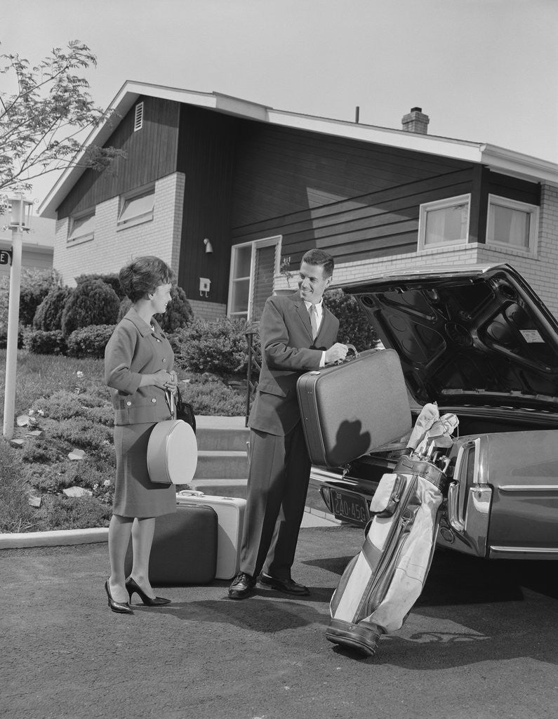 Detail of Couple man woman packing luggage into car trunk by suburban house by Anonymous