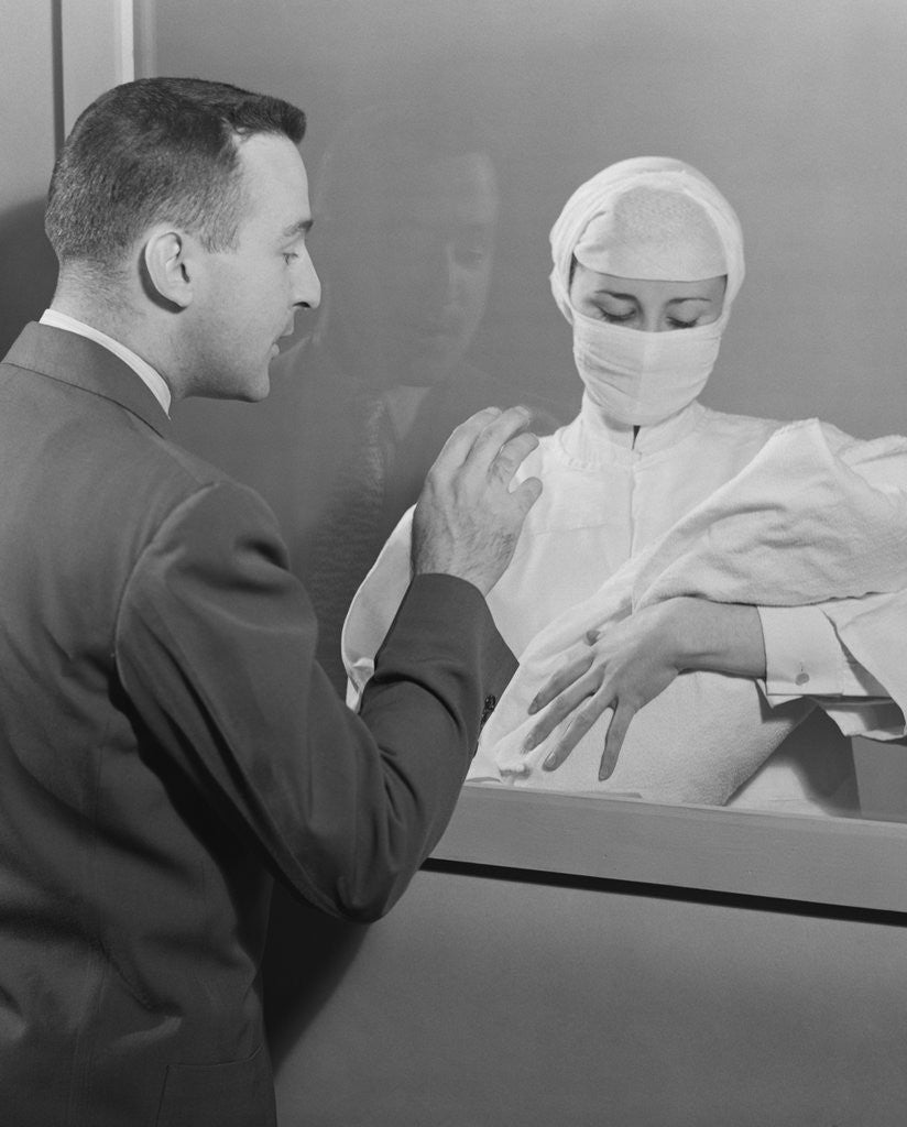 Detail of Female nurse holding infant up to father at nursery window by Anonymous