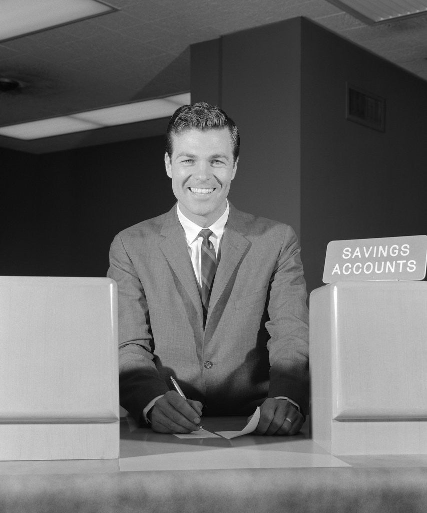 Detail of Smiling man bank teller savings accounts sign on counter by Corbis