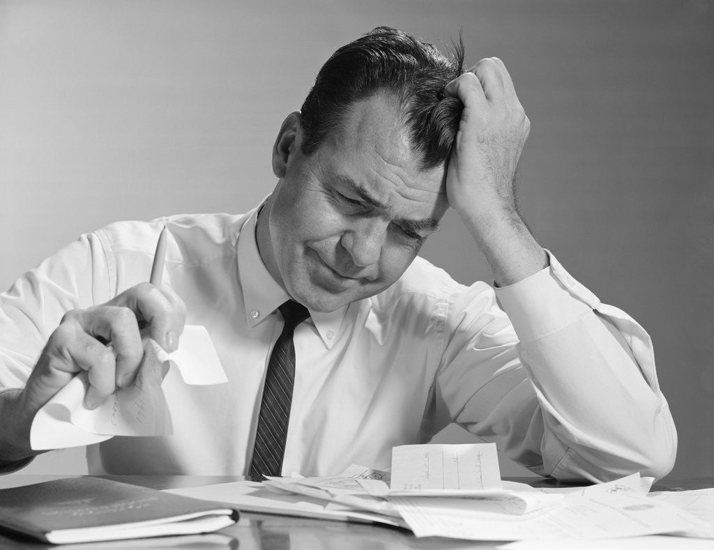 Detail of Frustrated businessman hand to forehead crumpling paper in hand by Anonymous