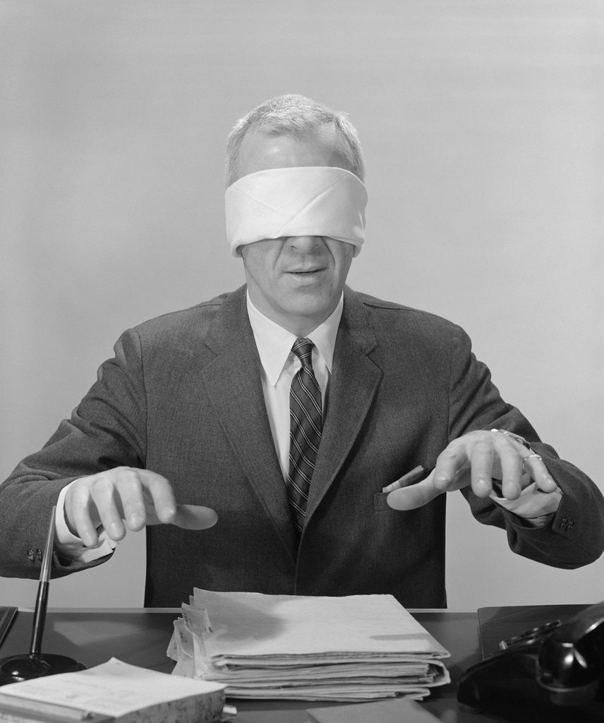Detail of Business man hands hovering over desk wearing blindfold by Anonymous