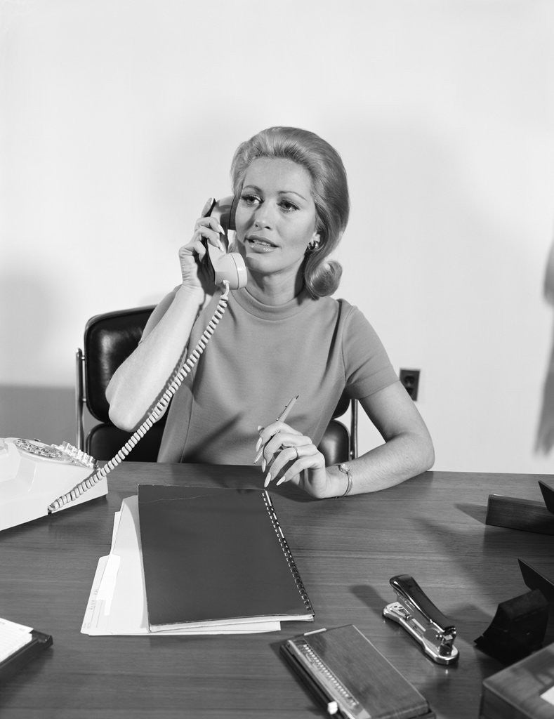 Detail of Blond businesswoman talking on telephone sitting at desk by Anonymous