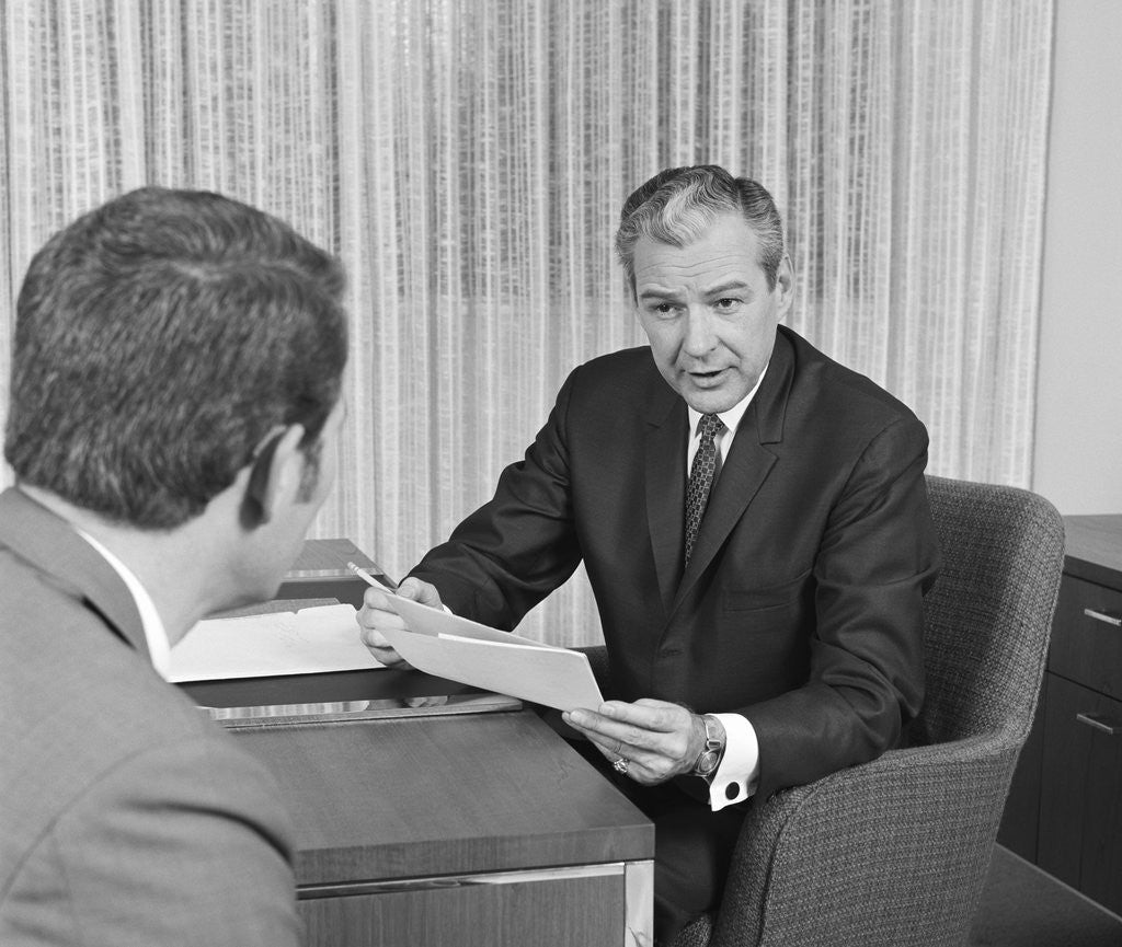 Detail of Man from behind meeting at desk of older businessman by Anonymous