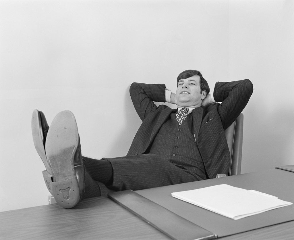 Detail of Confident young businessman sitting relaxed with feet up on desk by Anonymous