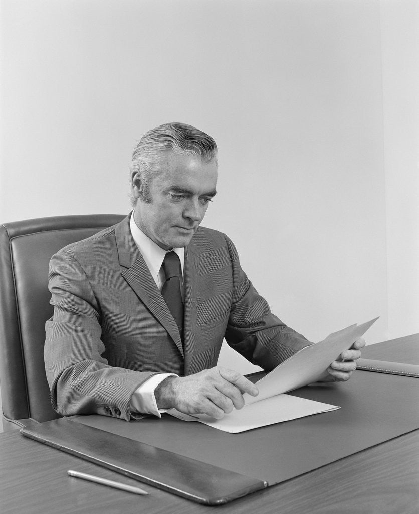Detail of Businessman executive middle aged sitting at desk reading papers by Anonymous