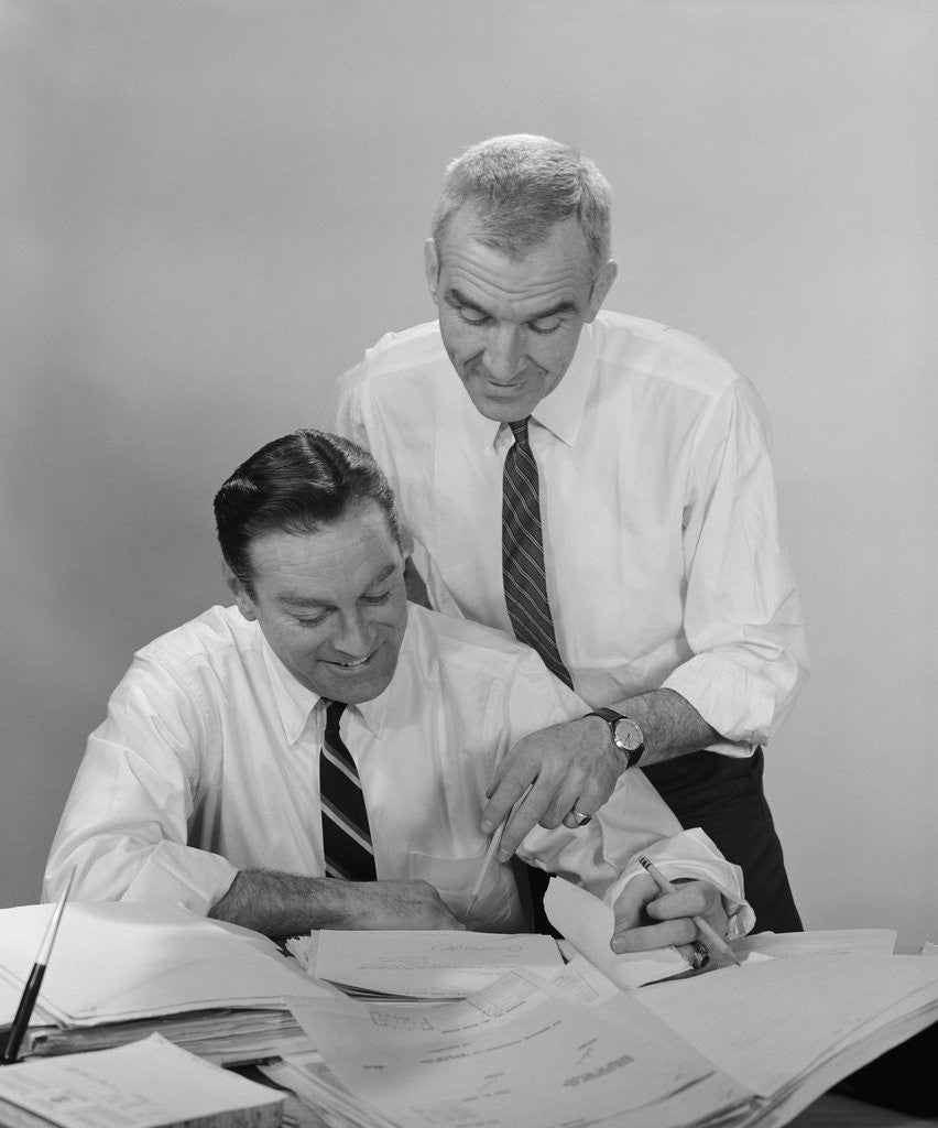 Detail of 2 businessmen in shirt sleeves looking over paperwork by Anonymous