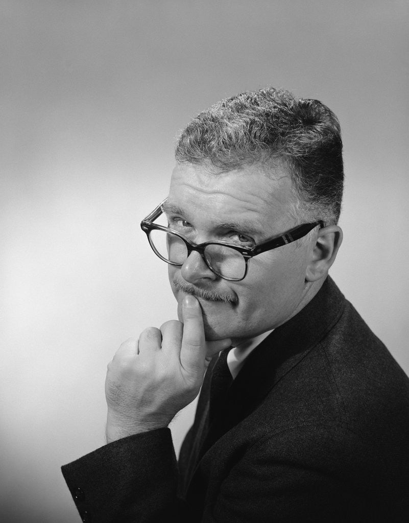 Detail of Middle aged man wearing eyeglasses low on nose quizzical facial expression by Anonymous