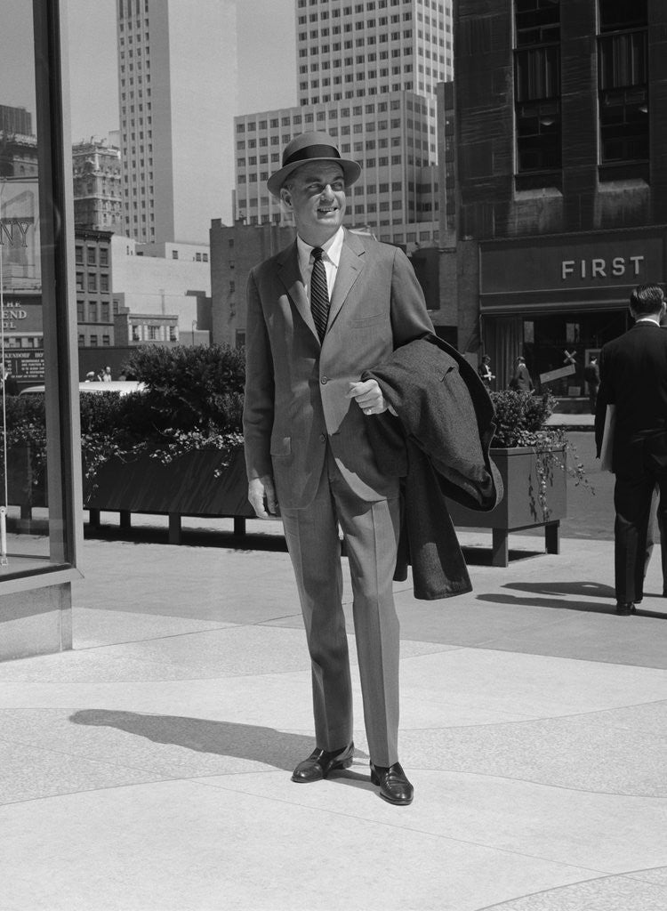 Detail of Businessman wearing suit hat carrying top coat standing on city street by Anonymous