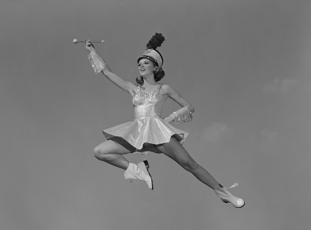 Detail of Woman majorette holding baton wearing short skirt uniform jumping into the air by Anonymous
