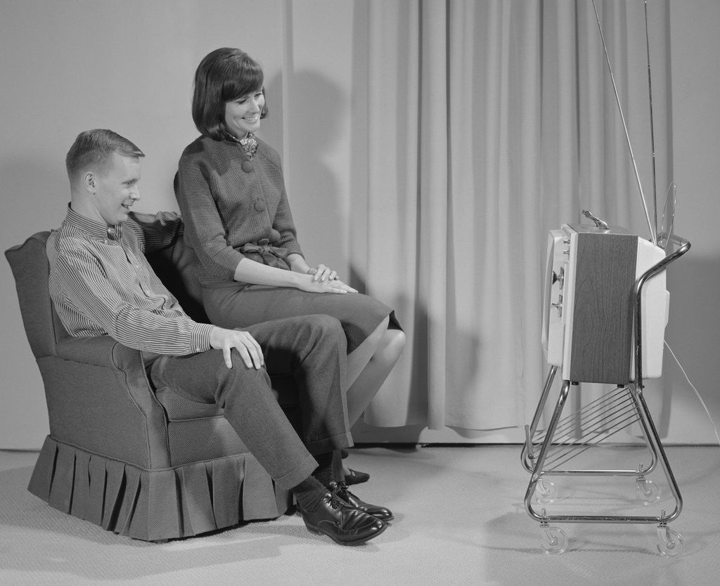 Detail of Couple man woman sitting chair watching portable television by Anonymous