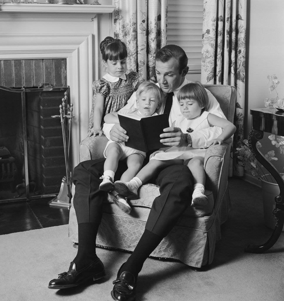 Detail of Man father sitting in chair with three children reading book by Anonymous