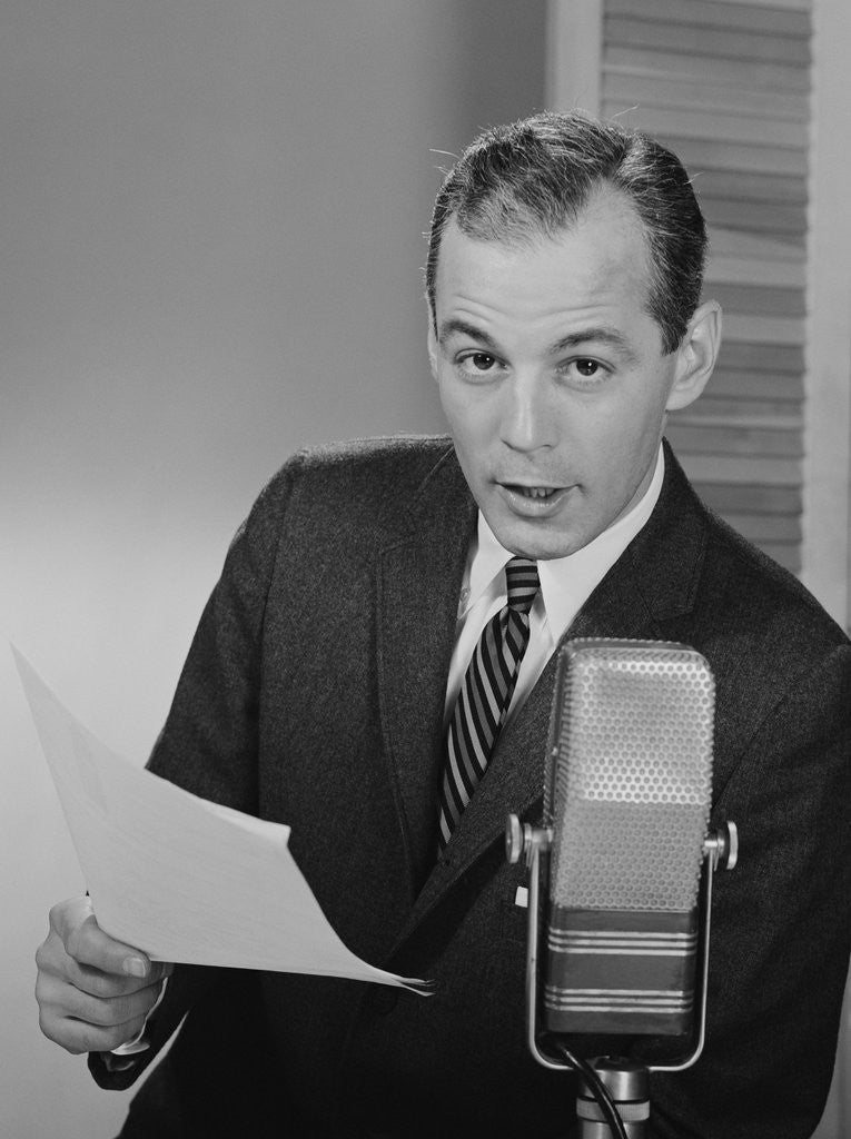 Detail of Serious man speaking into microphone holding papers newsman announcer broadcaster by Corbis