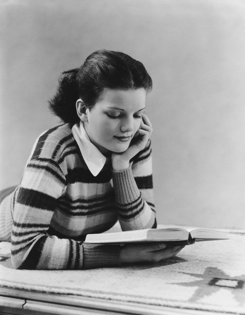 Detail of Young brunette woman teen striped sweater reading book studying by Anonymous
