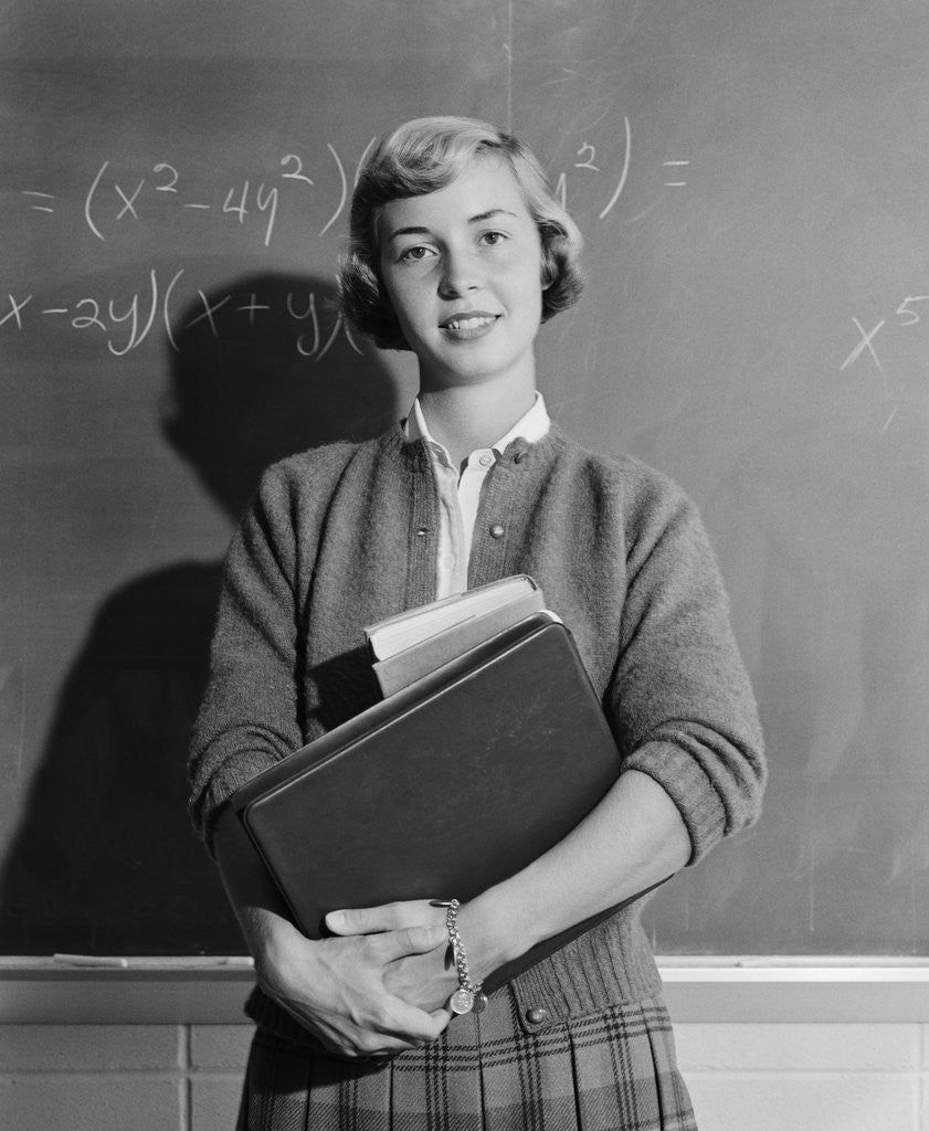 Detail of Teenage girl holding school books standing in front of blackboard by Anonymous