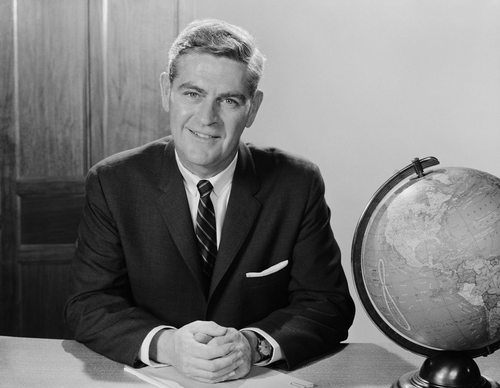 Detail of Smiling man sitting at desk with earth globe by Corbis