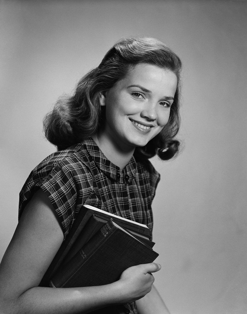 Detail of Young smiling woman holding books looking at camera by Anonymous